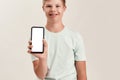 Close up of hand of disabled boy with Down syndrome holding smartphone with blank screen while standing isolated over