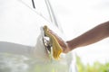 Close-up of hand disinfecting door handle of a car.