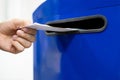 Close up hand drop letter and documents in the blue postbox in post office mail f