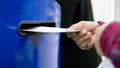 Close up hand drop letter and documents in the blue postbox in post office mail f