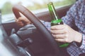 Close up hand Drunk young man while driving a car with a bottle of beer. Don`t drink and drive concept. Driving