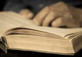 Close-up hand of an elderly man holding an open book. Stylized antique photo, retro. The old man opened the book. selective focus Royalty Free Stock Photo