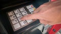 Close up of hand entering pin code at old Automated Teller Machine