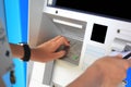 Close-up of hand entering PIN numbers with credit card on ATM bank machine