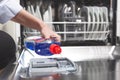 Close-up hand filling dishwasher with gloss liquid into the dishwasher box. Housework concept