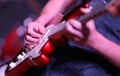 Close up shot of a hand strumming and playing a bright red electric guitar in a band