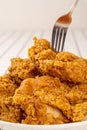 Close Up Hand and Fork on Fried Chickens on white Plate on table. Look Yummy and Yellow Gold Color