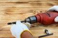 Close up hand with glove is preparing electric drill on wooden table Royalty Free Stock Photo