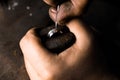 Close-up of hand of a goldsmith setting the diamond on the ring. Craft jewelery making with professional tools.