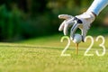 Close up hand Golfer woman putting golf ball for Happy New Year 2023 on the green golf for new healthy.