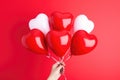 close-up of a hand holding balloons in the shape of a heart isolated on red background, Valentine& x27;s Day concept Royalty Free Stock Photo