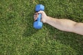 Close up on hand holding blue dumbbell in grass, view from above