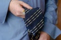 A close-up of a hand holding a blue and yellow striped tie. Royalty Free Stock Photo