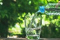 Close up hand holding bottle to pour water in the glass on nature and the sky background. Royalty Free Stock Photo