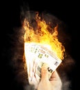 Close-up of hand holding burning bank notes waste of money concept