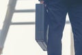 Close up hand holding business bag on the street. Unrecognizable businessman walking with a briefcase in a modern office. Royalty Free Stock Photo