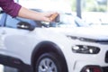 Close-up of a hand holding car keys with a blurred car in the ba