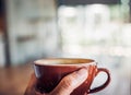 Close up hand holding a cup of hot cappuccino coffee cup with heart shape latte art blur cafe interior.food and drink concept.copy