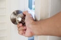 Close-up hand holding door knob, opening door slightly, selective focus