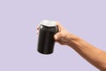 Close-up of hand holding Empty aluminum can with condensation isolated on purple