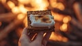 A close-up of a hand holding a freshly assembled s\'more, capturing the anticipation before the first bite.