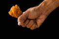 Close-up hand holding fried chicken on black background Royalty Free Stock Photo
