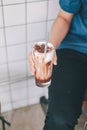 Close-up hand holding the glass iced chocolate latte fresh milk mixed with cocoa sauce and milk foam on top