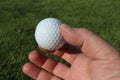 Close-up of a hand holding a golf ball. Green blurred background. Royalty Free Stock Photo