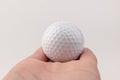 Female hand holding golf ball on light background. The white color of plastic ball is popular in the game Royalty Free Stock Photo