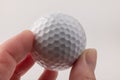 Female hand holding golf ball on light background. The white color of plastic ball is popular in the game Royalty Free Stock Photo