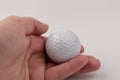 Female hand holding golf ball on light background. The white color of plastic ball is popular in the game Royalty Free Stock Photo