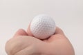 Female hand holding golf ball on light background. The white color of plastic ball is popular in the game Royalty Free Stock Photo