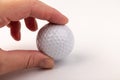 Female hand holding golf ball on light background. The white color of plastic ball is popular in the game Royalty Free Stock Photo