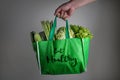 Close up a hand holding green grocery bag with Eat Healthy text