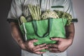 Close up a hand holding green grocery bag of mixed the organic g