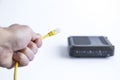 Close up of hand holding internet cable and modern modem in the background Royalty Free Stock Photo