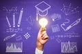 Close up of hand holding light bulb with creative knowledge and graduation sketch on purple wall background. Education, idea and Royalty Free Stock Photo