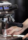 Close up hand holding of making coffee with machine in cafe. Professional modern espresso coffee machine pours hot drink into the Royalty Free Stock Photo