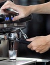 Close up hand holding of making coffee with machine in cafe. Professional modern espresso coffee machine pours hot drink into the Royalty Free Stock Photo
