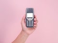 Close up hand holding mobile phone Nokia 3310 isolated on pink background. Female hand holding old used phone Nokia 3310 Royalty Free Stock Photo