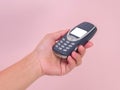 Close up hand holding mobile phone Nokia 3310 isolated on pink background. Female hand holding old used phone Nokia 3310 Royalty Free Stock Photo