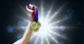 Close up of hand holding multiple medals against shining star lights and spots of light