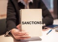 Close up of hand holding notepad with the word sanctions