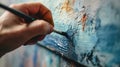 close up of hand holding painbrush drawing painting on canvas with blue color