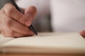 Close up of hand holding pen and writing on empty book paper, selective focus Royalty Free Stock Photo