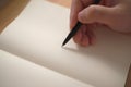 Close up of hand holding pen and writing on empty book paper, selective focus Royalty Free Stock Photo