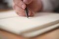 Close up of hand holding pen and writing on empty book paper, selective focus Royalty Free Stock Photo