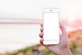 close-up hand holding phone mobile showing screen at outdoor during sunset time, mock-up new modern smartphone