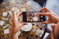 Close-up hand holding phone mobile taking photo coffee on table Royalty Free Stock Photo