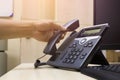 Close up on hand holding phone at office desk,Office phone and computer and keyboard.